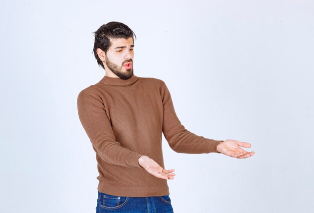 Photo of a young attractive man model standing and showing away with hands. High quality photo