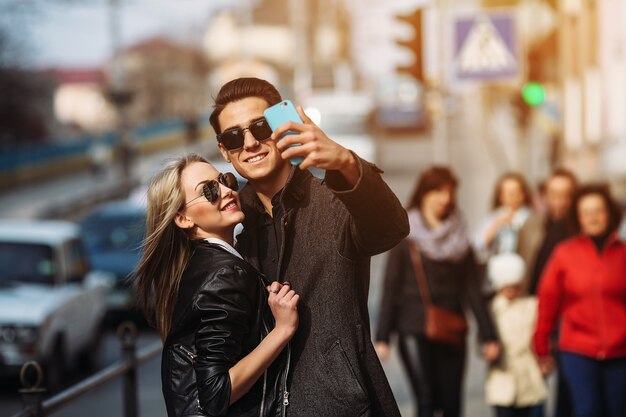 Photo of a young beautiful couple making selfie on a busy city street