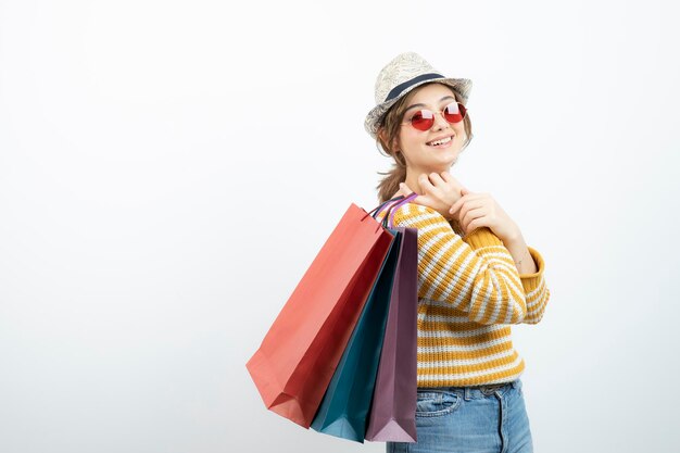 Photo of young brunette woman in sunglasses holding shopping bags. High quality photo