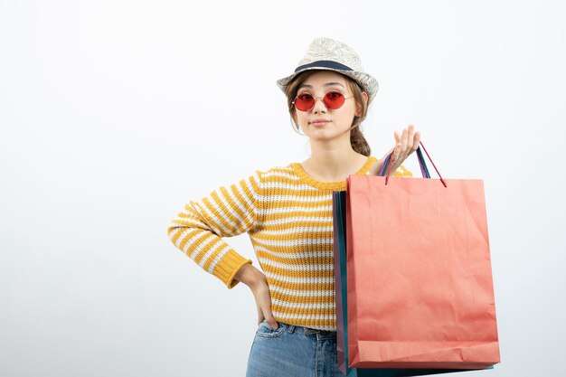 Photo of young brunette woman in sunglasses holding shopping bags. High quality photo