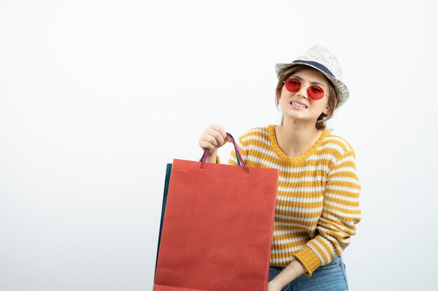 Photo of young brunette woman in sunglasses holding shopping bags. High quality photo