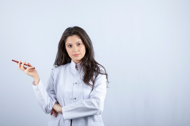 Photo of young doctor holding cellphone on grey. 