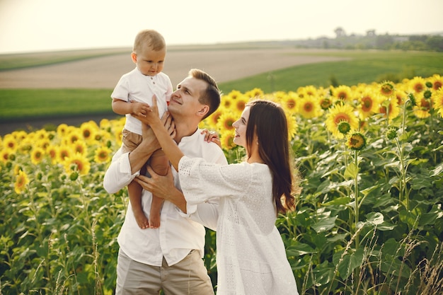 Photo of a young family at the sunflowers field on a sunny day.