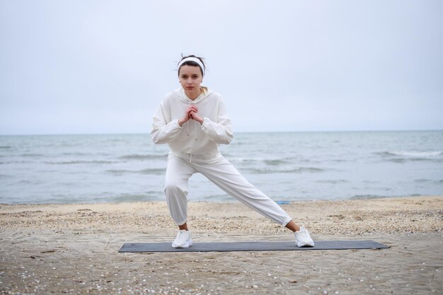 해변에서 일상적인 운동을 하는 젊은 여성의 사진 고품질 사진
