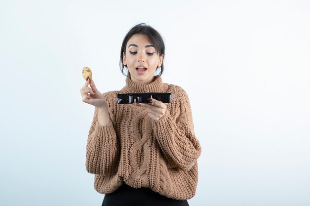 Photo of young girl eating chip cookies on white background. 