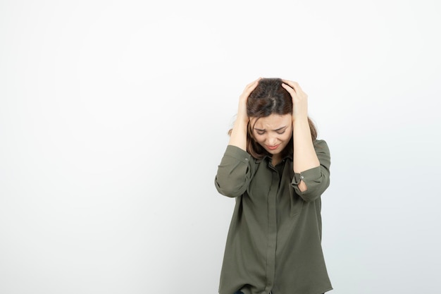 Photo of young girl having headache over white wall. High quality photo