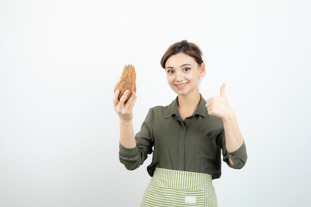 白の上に毛むくじゃらのココナッツを持っている少女の写真。高品質の写真