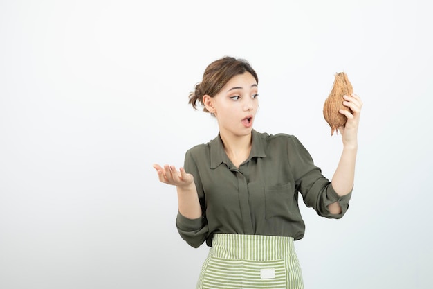 白の上に毛むくじゃらのココナッツを見ている若い女の子の写真。高品質の写真