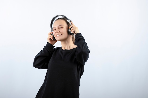 Фотография молодой девушки модели, слушающей музыку в наушниках