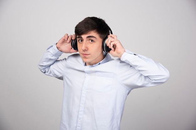 Photo of a young guy model standing in wireless headphones and looking at camera