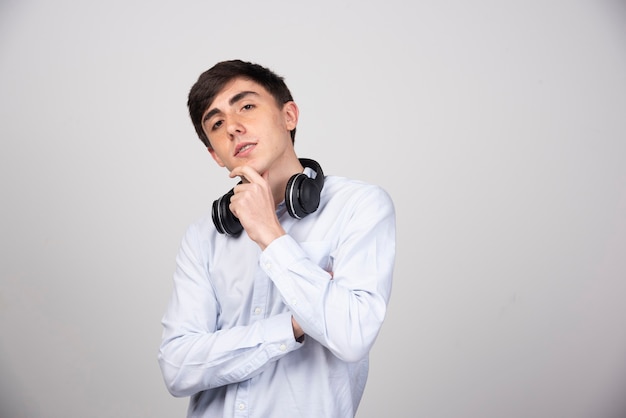 Photo of a young guy model standing in wireless headphones and looking at camera