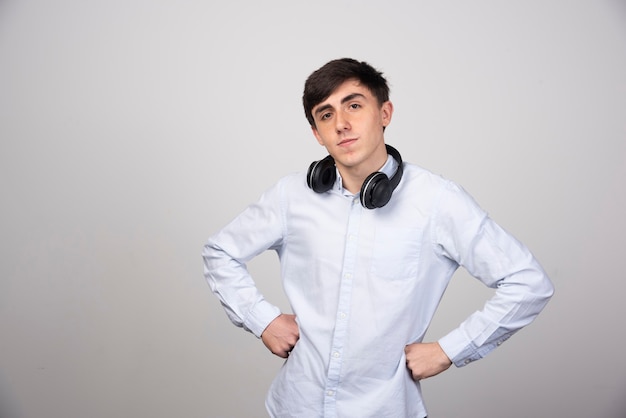 Photo of a young guy model standing in wireless headphones and looking at camera