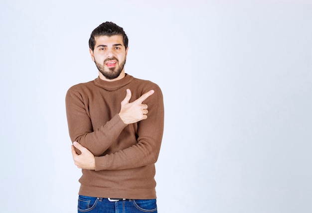 Photo of a young handsome man model standing and pointing up with an index finger. High quality photo