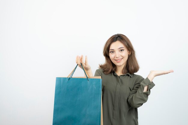 白の上に買い物袋を持っている若い幸せな女の子の写真。高品質の写真