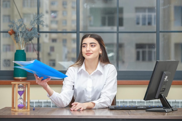 Foto gratuita foto di una giovane donna che tiene in mano un taccuino e prova a darlo a qualcuno