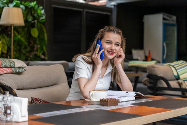 Photo of young lady sitting at the restaurant and talking on the phone