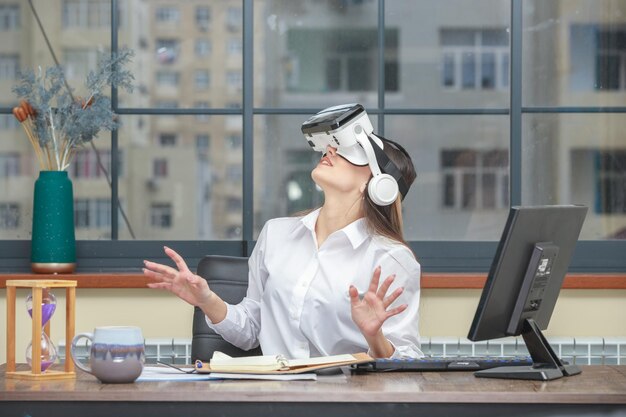 Photo of young lady wearing VR device and looking up at the office