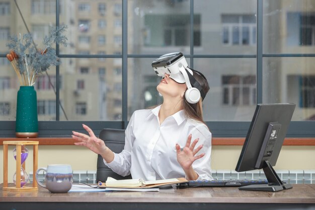 VRデバイスを身に着けてオフィスを見上げている若い女性の写真