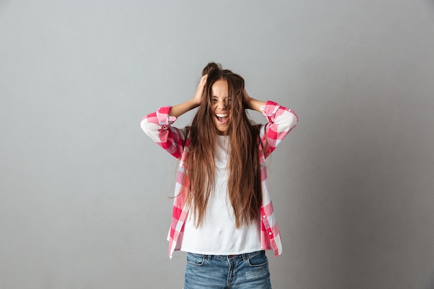 Photo of young long haired woman screaming and touching hair