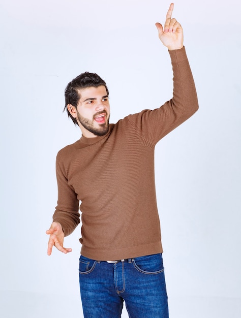 Photo of a young man model standing and showing up with hands . High quality photo