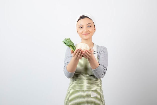 Photo of a young nice woman model in apron holding a cauliflower 