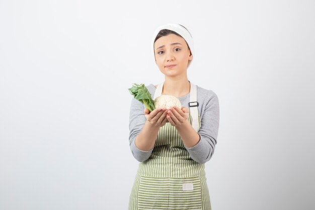 Photo of a young nice woman model in apron holding a cauliflower 