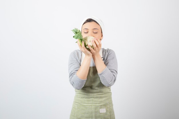 Photo of a young nice woman model in apron holding a cauliflower 