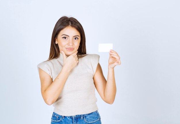 Photo of a young pensive woman model holding a card and posing.