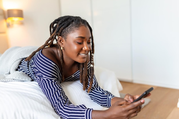 웃고 있는 젊은 아프리카 여성의 사진은 밤에 침실에서 침대에 누워 영상 통화를 하고 있다