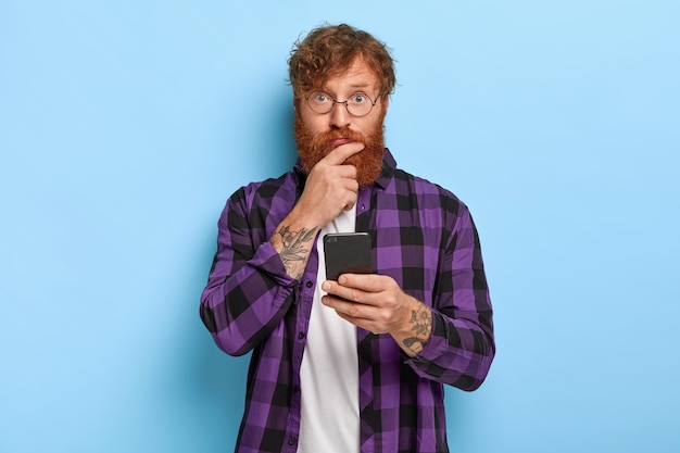 Free photo photo of young stylish ginger guy posing against the blue wall