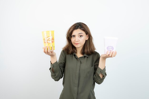 Photo of young woman in casual outfit holding popcorn. High quality photo