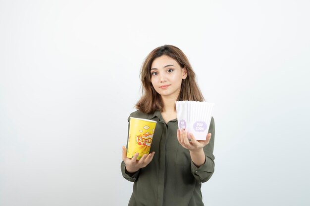 Photo of young woman in casual outfit holding popcorn. High quality photo