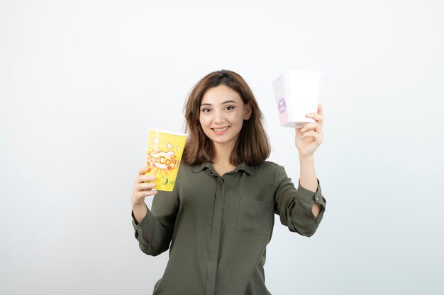 팝콘 상자가 서 있는 캐주얼 복장을 한 젊은 여성의 사진. 고품질 사진