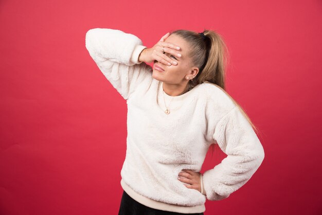 Photo of a young woman covering her eyes with her hands 