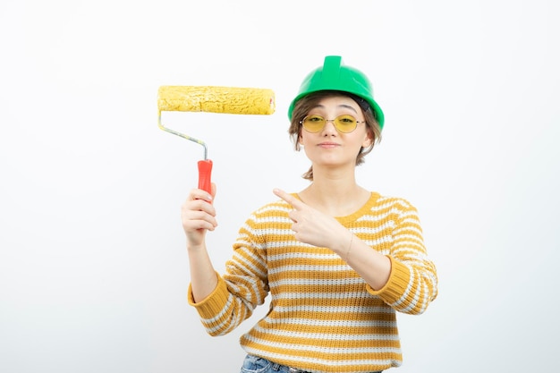 Free photo photo of young woman in green safety helmet holding a paint roller in her hand . high quality photo