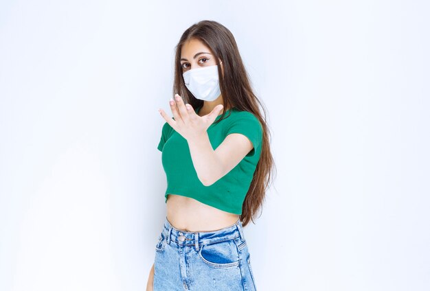 立って保護用医療マスクを着用している若い女性モデルの写真。