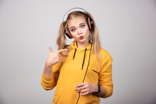 ヘッドフォンでポーズをとって音楽を聴いている若い女性の写真。