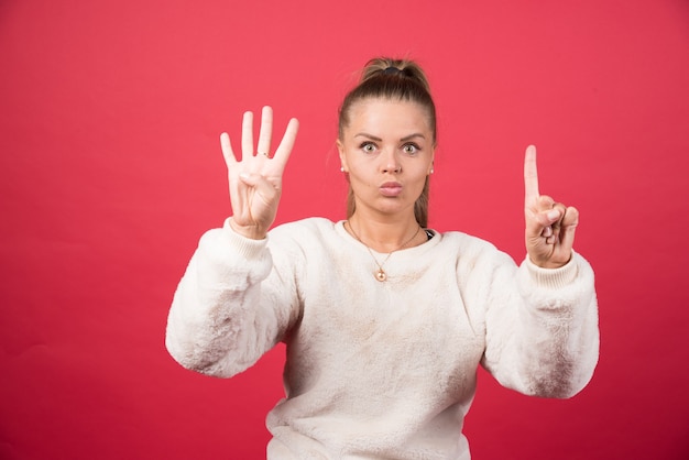 Photo of a young woman showing four and one with fingers