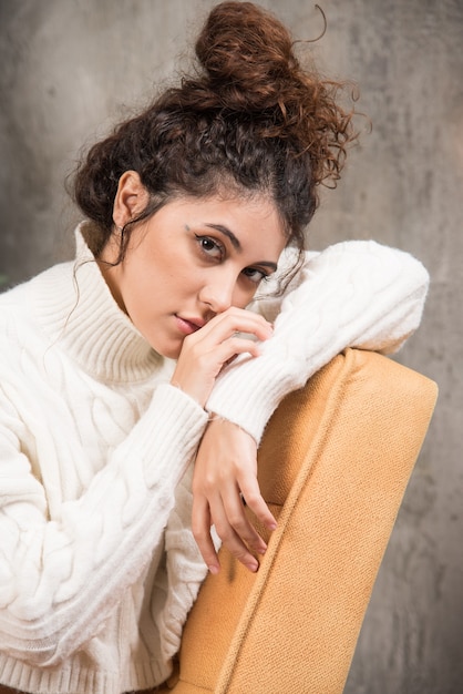 Photo of young woman sitting in comfy chair near Christmas tree