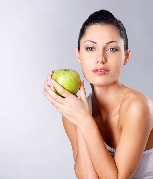 青リンゴを持つ若い女性の写真。健康的な食事の概念。