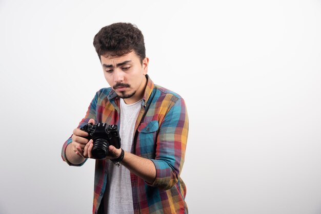 Photograph looking at his camera and thinking .