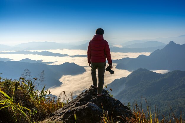 Фотограф рука камеры и стоя на вершине скалы в природе. Концепция путешествия.