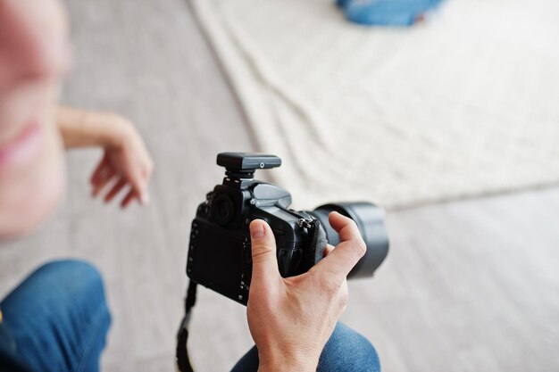 Fotografo che spara mani da vicino e modella in posa sullo sfondo in studio