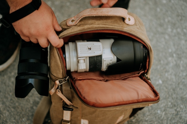 Photographer taking out a white camera lens from a camera bag