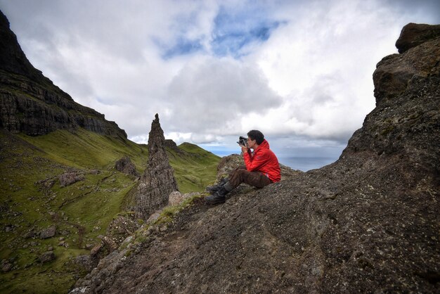 photographer taking a photos sitting on a rock of a mountain