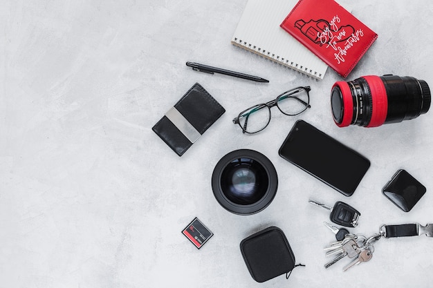 Photographic equipment, spiral notebook and personal accessories on background