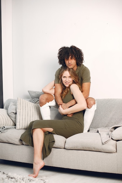 Photoshoot.Happy young couple at home on sofa. Hugging, kissing.