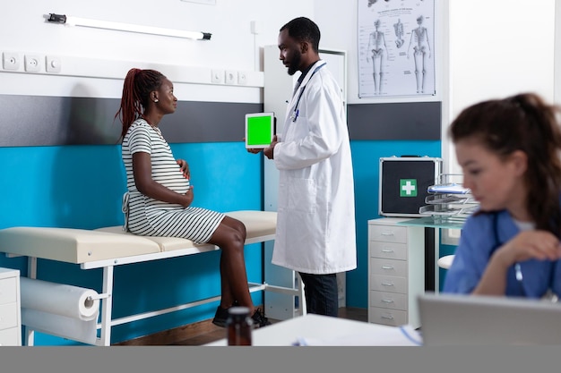 Physician showing tablet with vertical green screen to woman