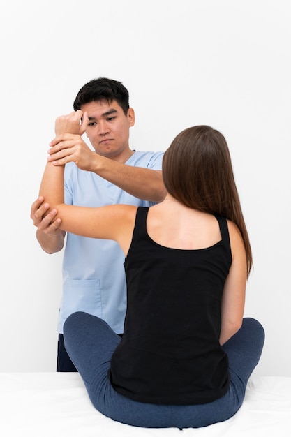 Physiotherapist doing elbow exercises with female patient