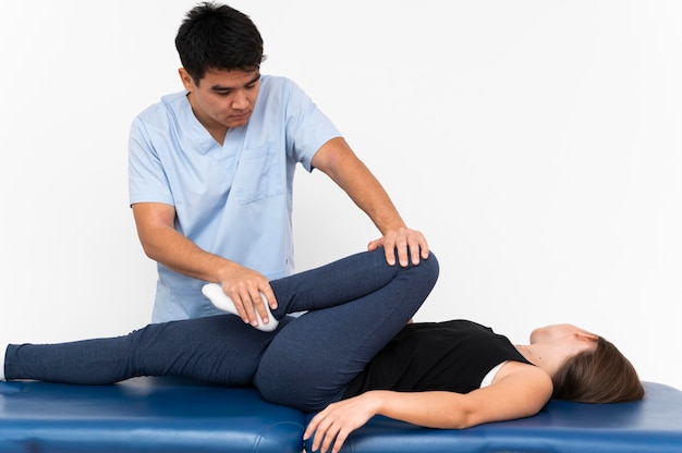 Physiotherapist doing leg exercises with female patient